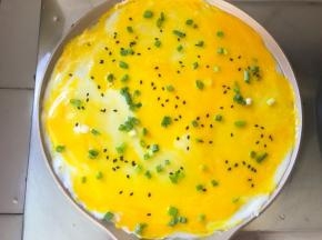 将鸡蛋抹均匀，撒上香葱和芝麻，煎至鸡蛋凝固