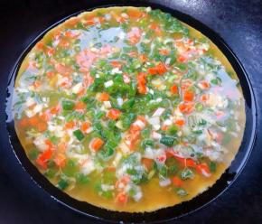 锅中倒入底油加热倒入拌匀的豇豆胡萝卜蛋液