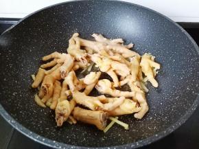 炒锅置油烧至三层热，把葱姜蒜炒香再放入鸡爪炒。