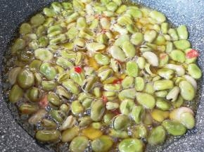 炒锅内倒入食用油烧热，下入煮好的蚕豆。