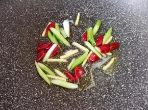 炒锅内倒适量的食用油烧热，下入姜丝、葱段和干红辣椒炒香。