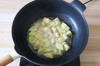 将茄块倒入油锅中炸至表面定型后再翻动，使茄块受热均匀，炸至表面金黄后捞出；