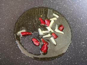 炒锅内倒适量的食用油烧热，下入姜丝和干红辣椒炒香。