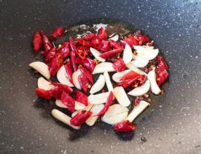 炒锅内留余油，下入蒜片、辣椒段和花椒。