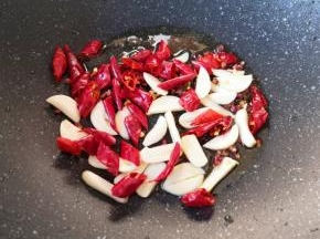 炒锅内留余油，下入蒜片、辣椒段和花椒。