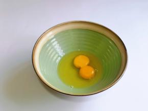 首先取一个大口碗，磕入两枚鸡蛋，用手动打蛋器打散。