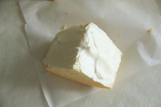 取一块戚风胚，尖角朝上，用锯齿刀从中切开一部分，千万不要切断。然后用抹刀将夹层里填满酸奶冰乳酪酱。然后在切面上也涂抹一层冰乳酪酱。