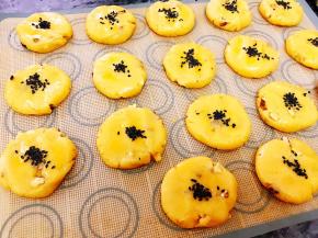 把面团分为30克左右一个，轻轻压扁后刷上全蛋液撒上黑芝麻