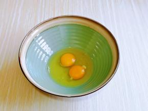 首先将鸡蛋磕入大口器具中。