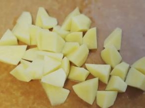 1.炸薯角，最好用黄心土豆，做出来的薯角内部才会特别软糯，把黄心土豆的外皮用削皮刀刮去，然后切成滚刀块