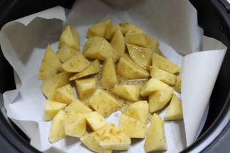 4.往空气炸锅里铺一层耐高温的油纸，然后摆上土豆块，垫油纸，主要是为了好清洁，这样烤都不用洗锅了，把油纸一扔就可以