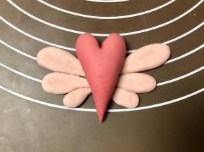 同样的方法把另一边翅膀也做好，对称摆放，把红色爱心面团放在翅膀中间。