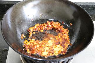 倒入生姜粒、大蒜粒煸炒出香味后倒入郫县豆瓣酱煸炒出红油，翻炒均匀后倒入虾黄煸炒一会儿；