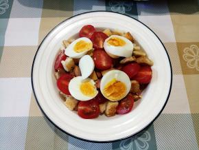 取一个盆，装入吐司丁、火腿肠圈，撒一把大杏仁和开心果仁，放上圣女果和鸡蛋。