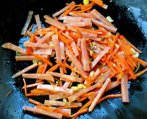 锅中放入底油放入蒜粒爆香再放人胡萝卜和火腿炒匀