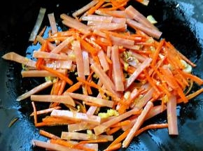 锅中放入底油放入蒜粒爆香再放人胡萝卜和火腿炒匀