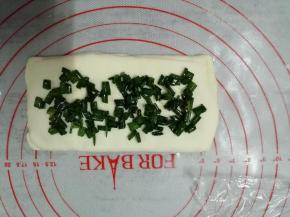 上面的部分向下盖合，两端捏紧，防止馅料露出来。再用擀面棍轻压两边擀长，在上面继续撒馅料