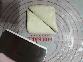 把面皮对折，成一个方形，用擀面棍再轻轻擀压一下，用切面刀对角切开，成两个三角形，这样可以做出6个烤饼胚