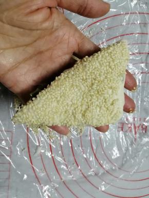 在饼胚表面刷上蜂蜜水或者糖水（比例是1比1，这样芝麻不容易掉落），在炒熟白芝麻上按一下，只粘一边，要粘得密密麻麻才更香，也好看