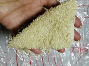 在饼胚表面刷上蜂蜜水或者糖水（比例是1比1，这样芝麻不容易掉落），在炒熟白芝麻上按一下，只粘一边，要粘得密密麻麻才更香，也好看