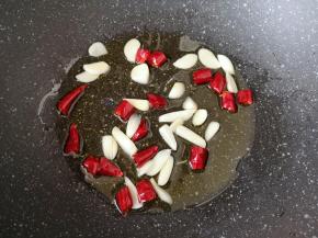 炒锅内倒适量的食用油烧热，下入蒜片和干红辣椒炒香。