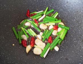 锅里继续倒入食用油烧热，下入葱、蒜和干红辣椒炒香。