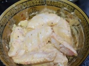4.加入一勺植物油，用手将各种调味料和鸡翅抓匀腌制一个小时。鸡翅表面能裹上一层薄薄的面粉糊最佳，现成的cook100法式黑椒烤肉料里盐和其它配料的用量都搭配好了，比自己乱搭的味道要好，特别像饭店里的鸡翅味道，不要在另外添加盐和其它调味料了。