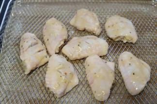 5.将腌制好的鸡翅取出来，均匀的挂上一层稀面糊，放入烤箱的空气炸烤网上。生姜这时可以丢弃不要