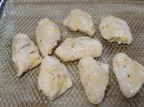 5.将腌制好的鸡翅取出来，均匀的挂上一层稀面糊，放入烤箱的空气炸烤网上。生姜这时可以丢弃不要