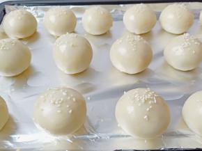 包好的面团放在油锡纸上，面团刷一层蛋黄液，撒一点白芝麻。