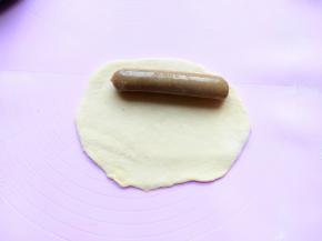 取出一份擀成长方形，比牛肉肠略长一点。
将擀好的面团反面底边压薄，放上牛肉肠从上而下卷起来，收口处捏紧。