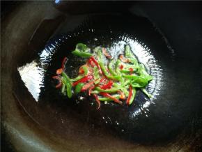 锅内倒入比一般炒菜稍微多一点的油，先下辣椒丝炒至断生。