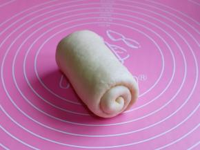 取一块松弛好的面团，用擀面杖擀长舌状，由上往下卷起来，依次卷好。