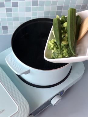 东菱早餐机的煮锅倒入适量水，烧开后下入秋葵和西兰花，焯烫3分钟左右。