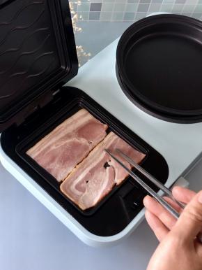 培根从中间切开，放入三明治机中，因为培根本身油脂就很丰富，可以不用刷油，盖上三明治机，煎制3分钟。