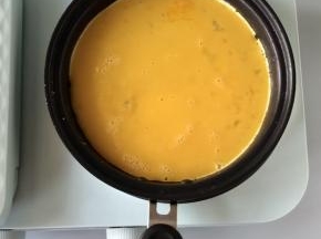 油热后，火力调至低档，倒入一半的鸡蛋液，煎至底部凝固。