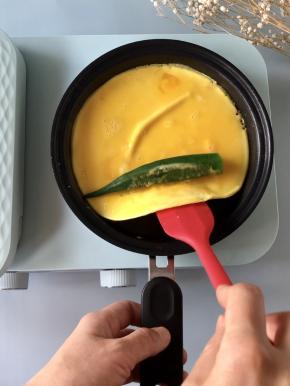 鸡蛋液煎至半凝固的状态，放入一根焯熟的秋葵，然后借助铲子卷起。