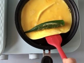 鸡蛋液煎至半凝固的状态，放入一根焯熟的秋葵，然后借助铲子卷起。