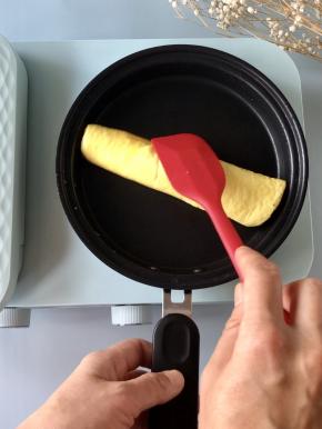 卷起后继续保持低档的火力，把蛋液煎制全熟。同样的方法把剩下的蛋液和秋葵再煎一个蛋卷。