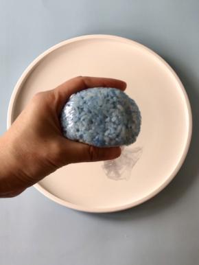 取一张保鲜膜，把蓝色米饭放在保鲜膜中间，然后借助保鲜膜把米饭裹起来，捏出河马的头。