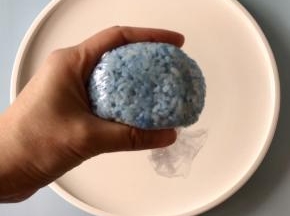 取一张保鲜膜，把蓝色米饭放在保鲜膜中间，然后借助保鲜膜把米饭裹起来，捏出河马的头。
