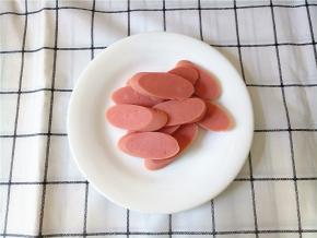 火腿肠切斜片，尽量切均匀一些，一样长一样厚，有些人也喜欢对半切开，随意。如果有方火腿就更好了，没有就火腿肠了。