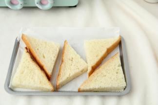 烤盘垫好油纸。用锯齿刀将吐司对角切开，一块吐司切两刀。均分成4块。排入小烤盘。我这个烤盘排了5小块。