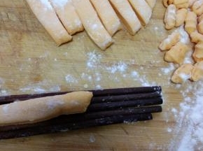 拿4根筷子，把切好的面条放在筷子上，用刀切成一小块，向外按压面团，就成了海螺的形状