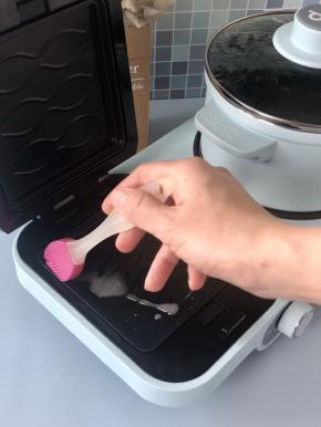 煮锅在烧水的时候，可以同时用三明治机来煎鸡蛋，在三明治机中上下盘刷适量食用油。