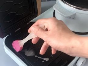 煮锅在烧水的时候，可以同时用三明治机来煎鸡蛋，在三明治机中上下盘刷适量食用油。