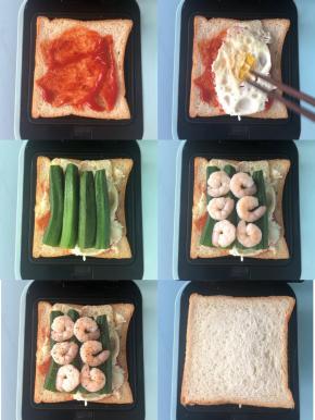 三明治机的下盘放入一片吐司片，抹上番茄酱，依次放上煎蛋、秋葵（切掉尖部）、虾仁，磨上黑胡椒碎，再盖上一片吐司片压好，然后盖好上盘，设置3分钟。