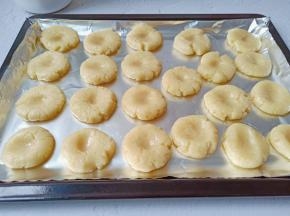 揪一个小面团，揉搓成圆形，放入烤盘里，用拇指在面团中间按一下，防止烤的时候鼓包。