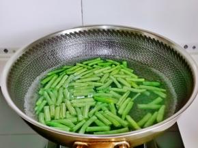 刀豆焯水，锅中水烧开后下刀豆段，加2克盐，滴几滴食用油，大火煮2-3分钟，捞出过冷水。