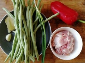准备材料。四季豆摘掉头尾和豆筋然后清洗干净。五花肉切成薄片清洗干净沥干水分备用。红椒、葱、姜片、蒜洗干净备用。